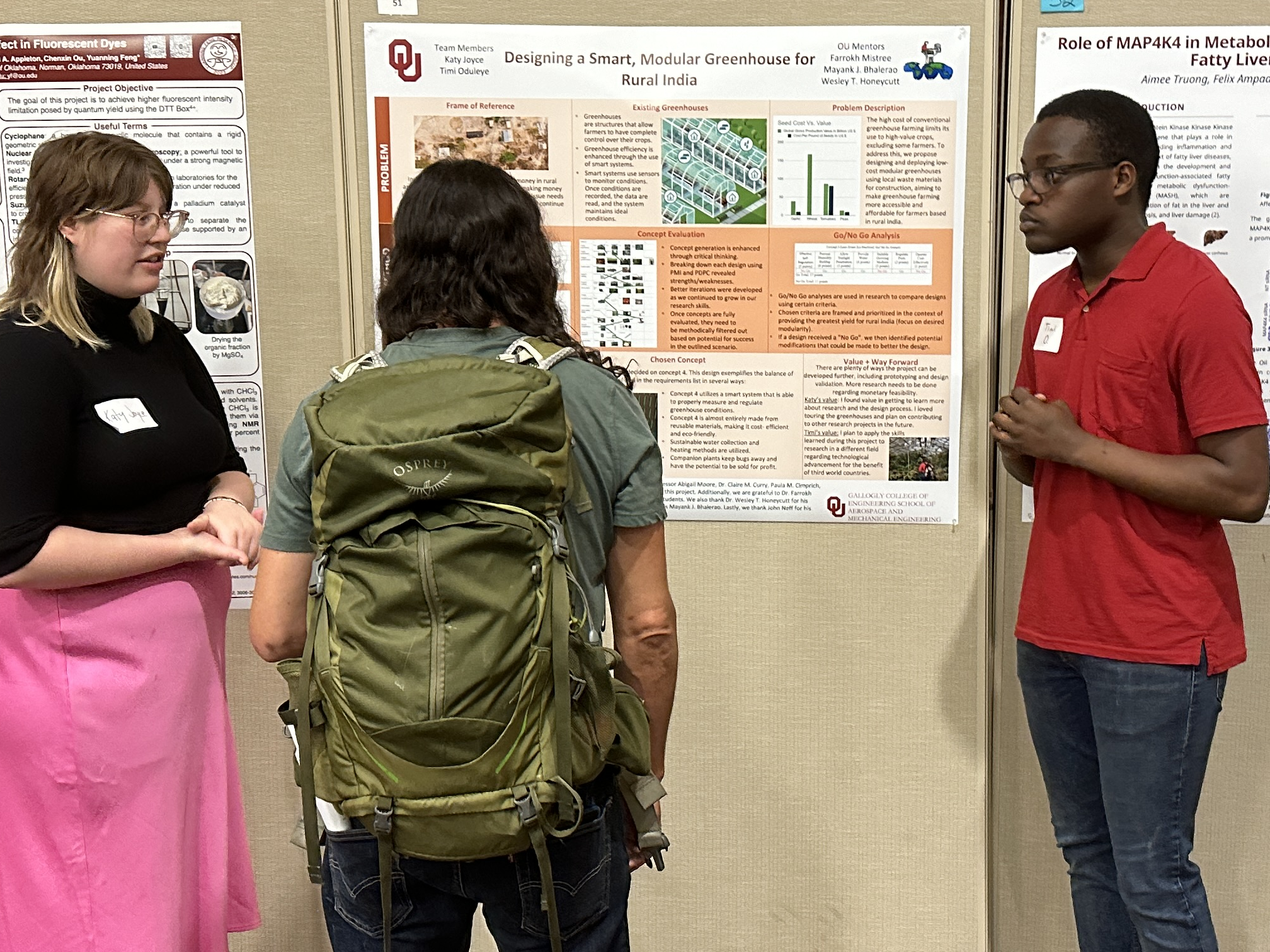 A candid photo of Katy and Timi presenting their poster to a researcher.