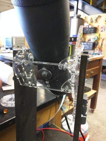 A spotting scope is attached to the cradle of the altitudinal axis